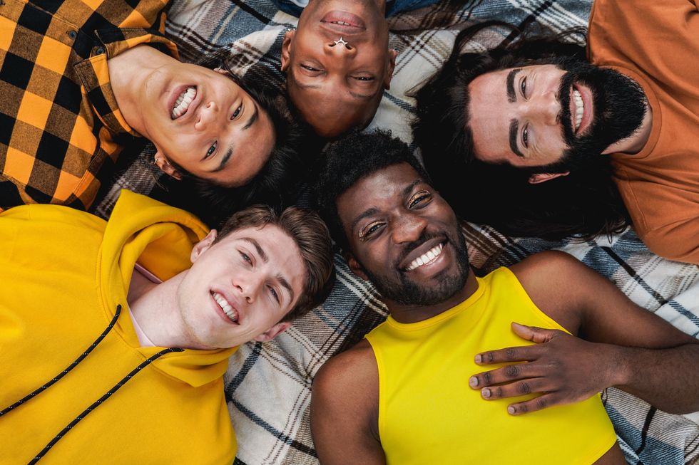 a group of diverse men laying down and smiling