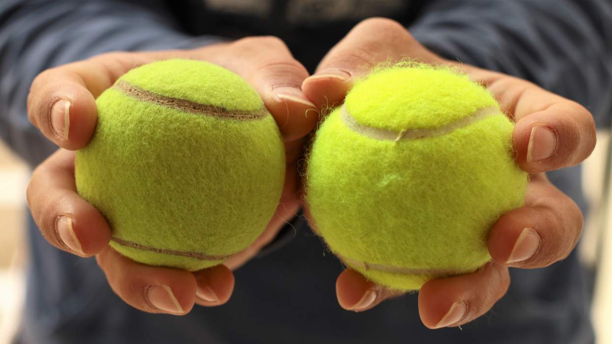 A man holding two tennis balls.