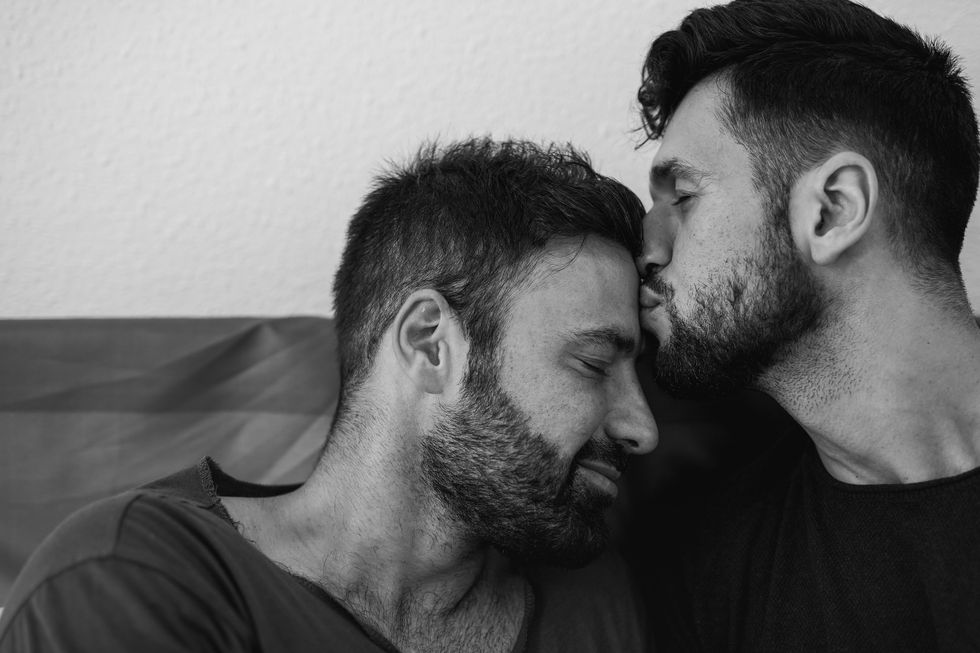A man kissing another man on the forehead