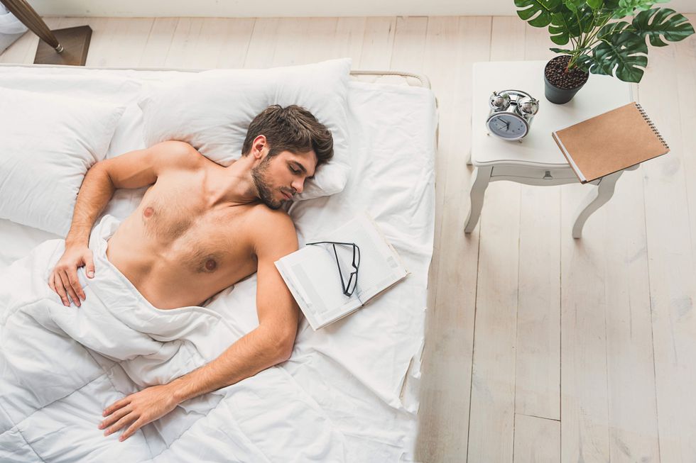 A shirtless man taking a nap in bed