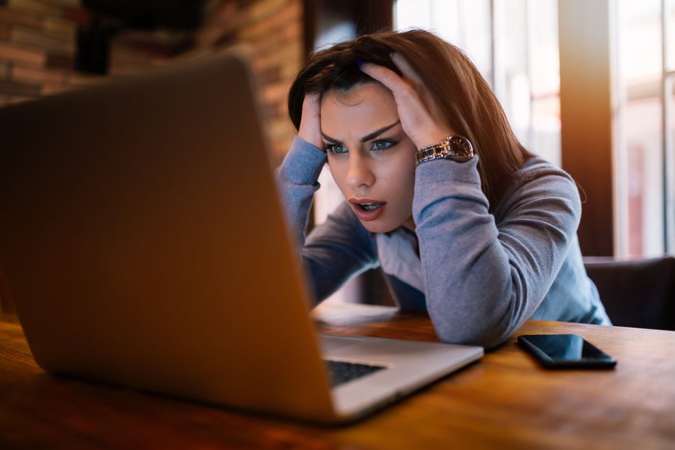 A woman gripping her head while looking at her computer