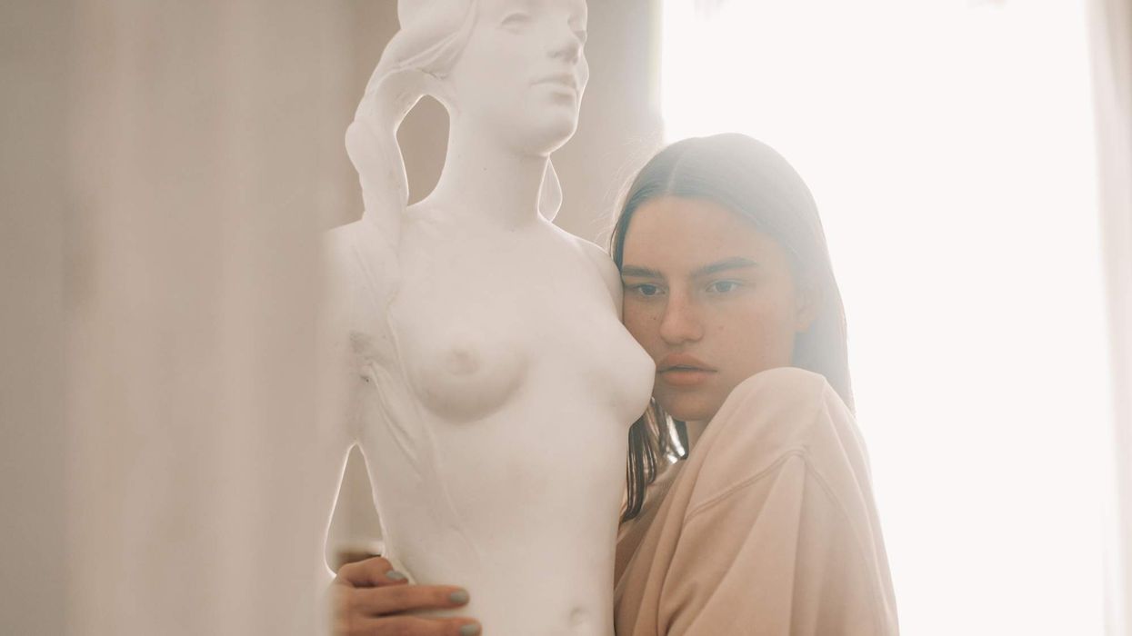 A woman hugging a stone statue of a woman