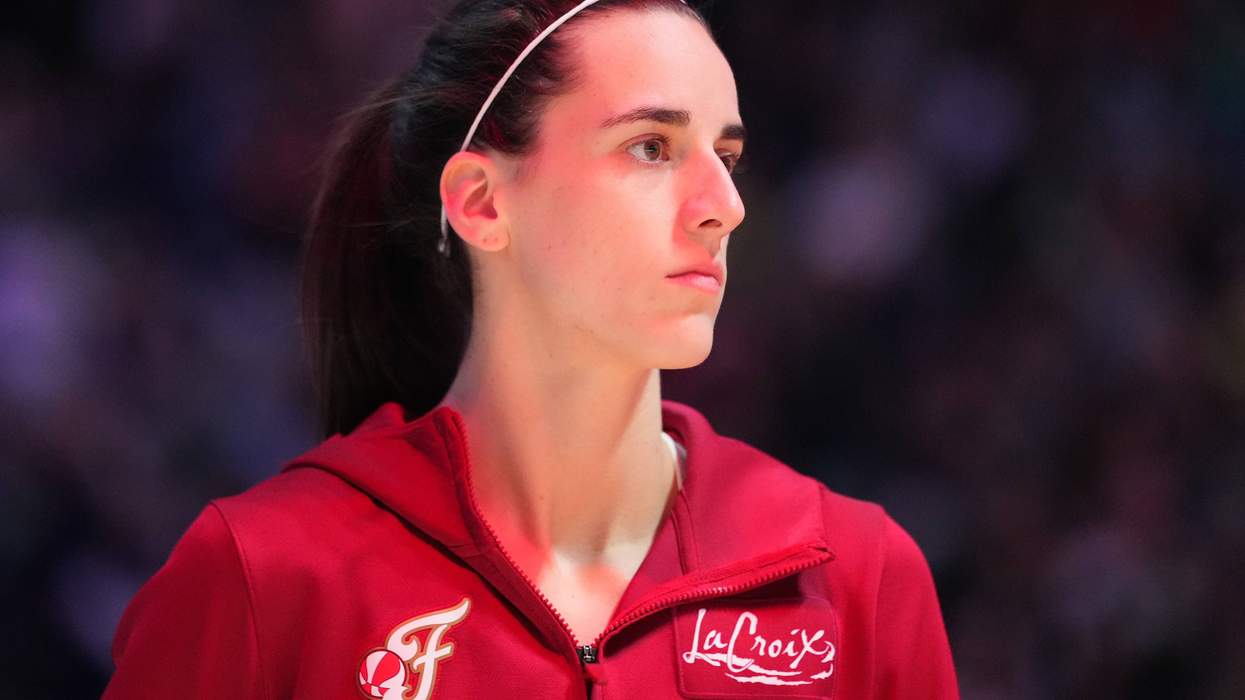 A woman in a red jacket looks contemplative, with a dark blurred background.