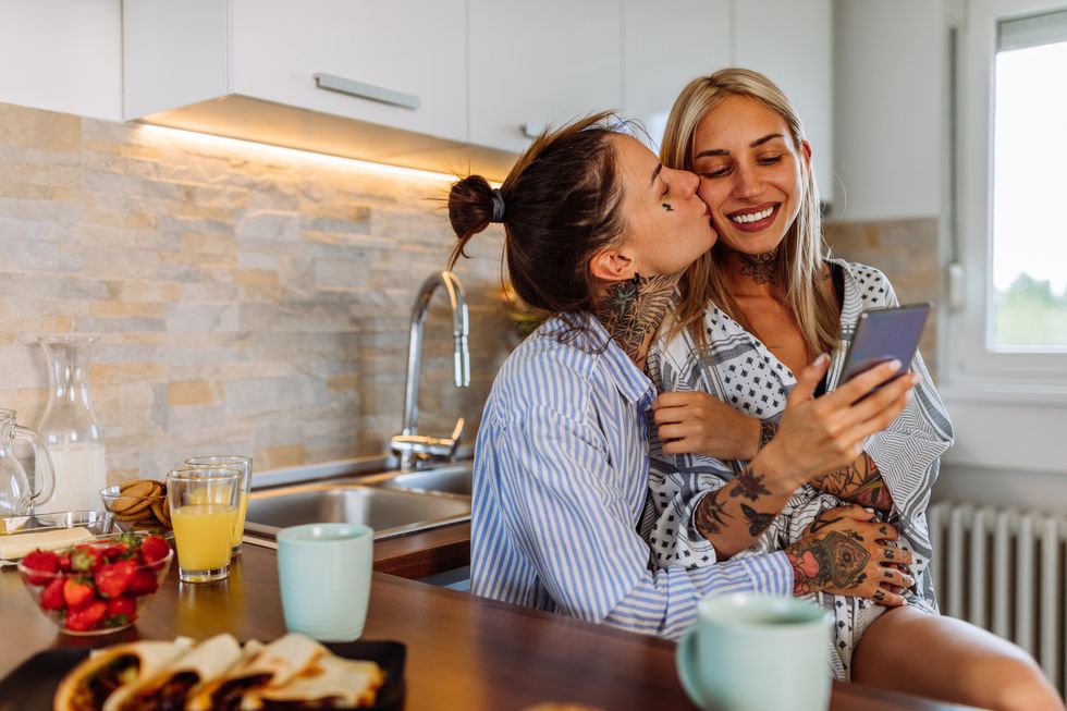 a woman kissing her partner who is sitting in her lap