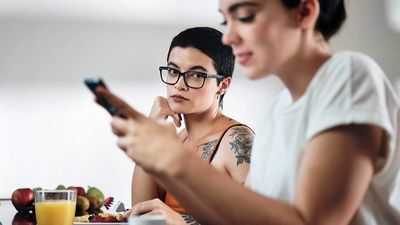 A woman looking at another woman who is holding a cell phone