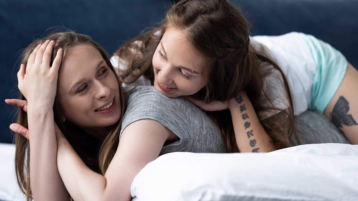 A woman lying in bed with another woman laying on her back