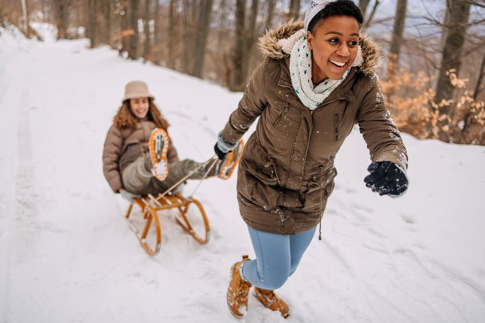 A woman pulling another woman on a sled