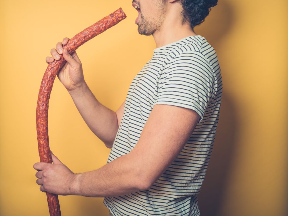 A young man is about to put a very big sausage in his mouth