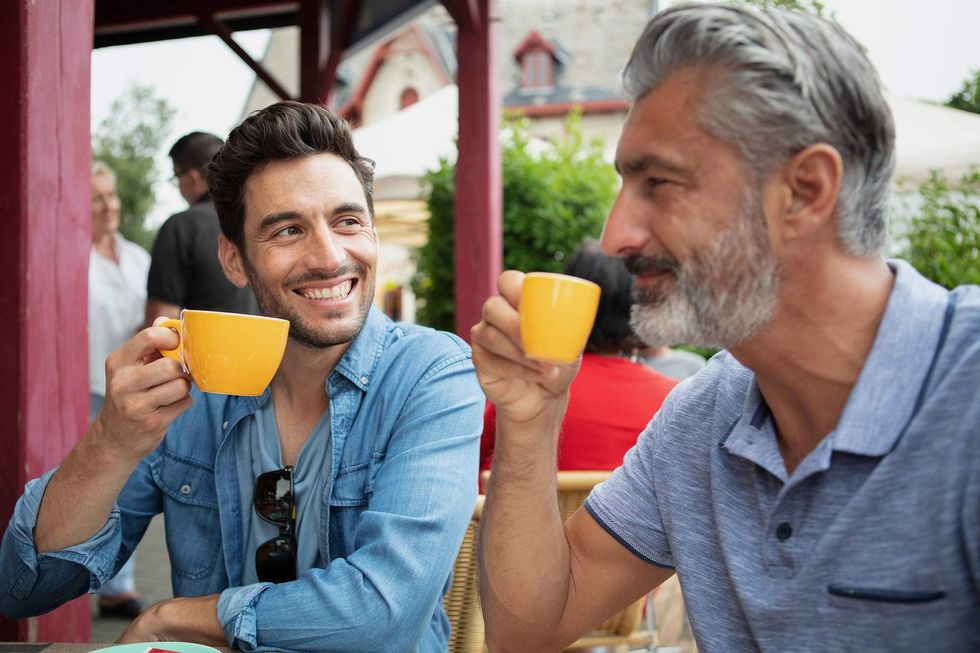 a younger man having coffee with an older man