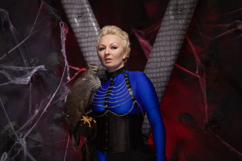 beautiful scary woman with the big hawk best friend on the background of dark room