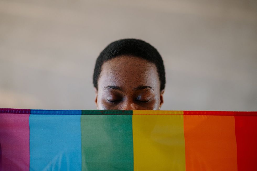 Black woman behind a Pride flag
