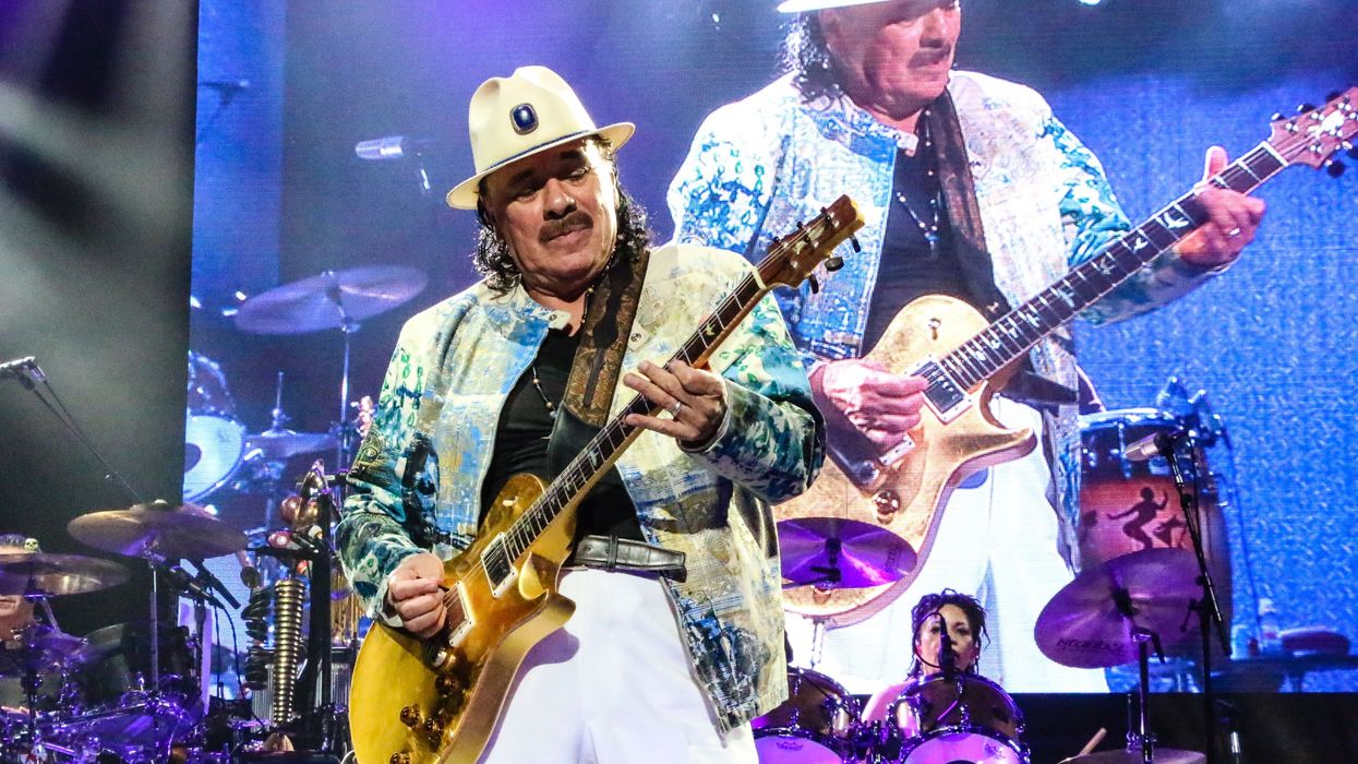 Carlos Santan playing guitar on stage at a concert.