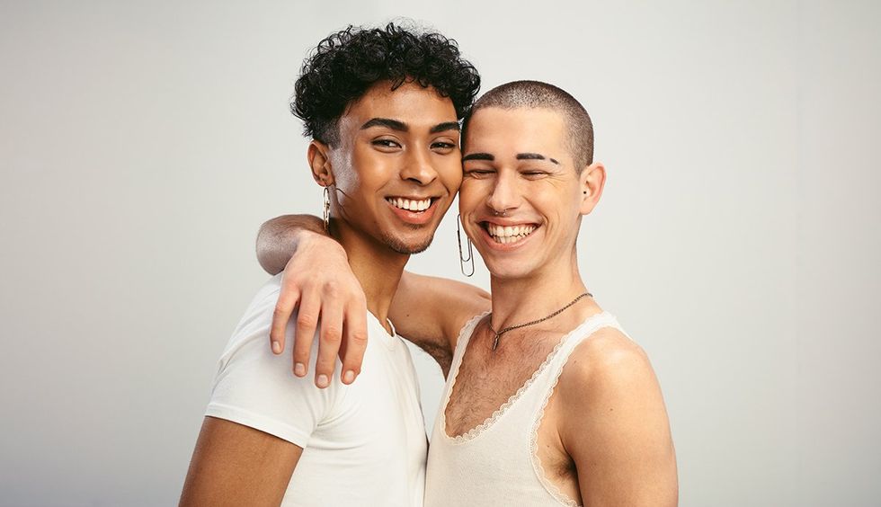 Cheerful male couple smiling on white background. Two men standing together and looking at camera.