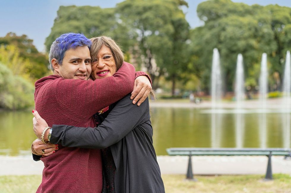 Cheerful queer couple hugging in a park looking at the camera