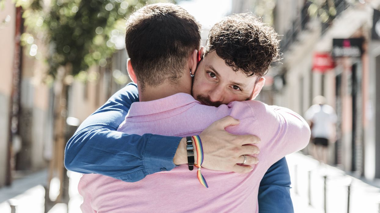 Close-up of a gay couple hugging each other while standing on paved street in sunny day