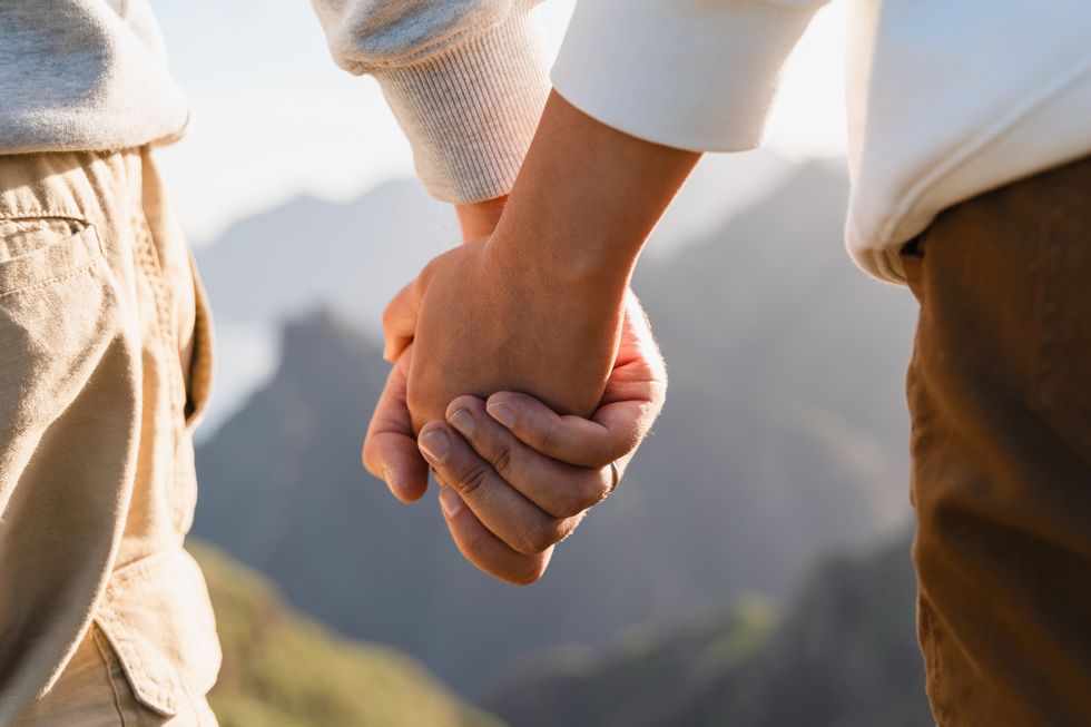 Couple hold hands in mountains nature. Friends or lovers holding hands while walking outdoors.