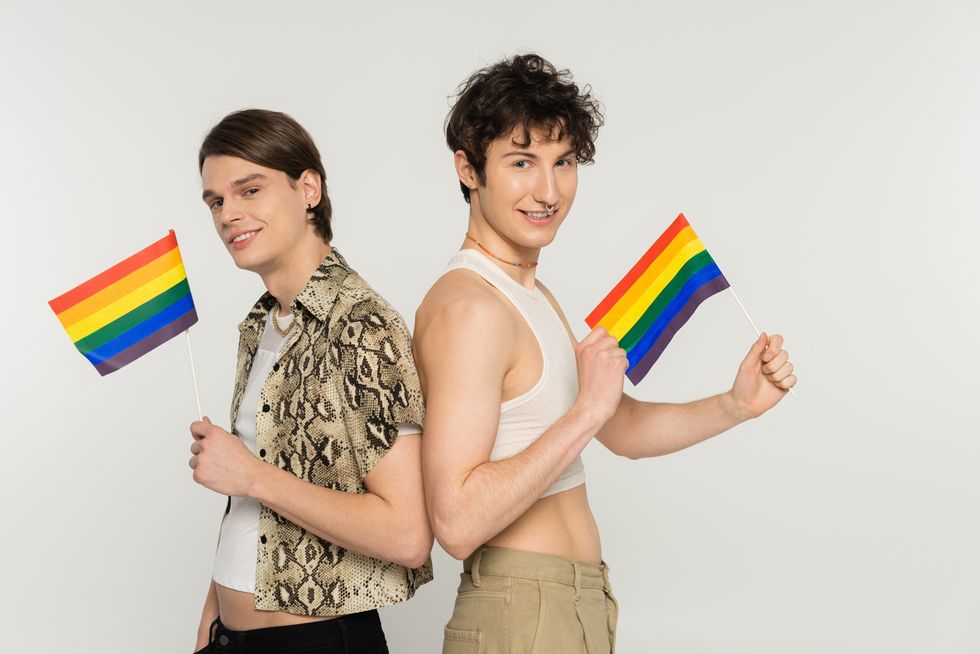 couple with pride flags back to back smiling