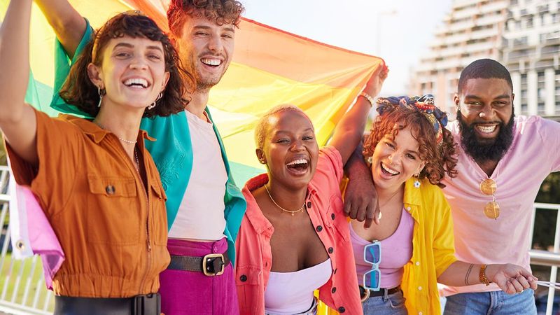 diverse gen z friends holding a pride flag