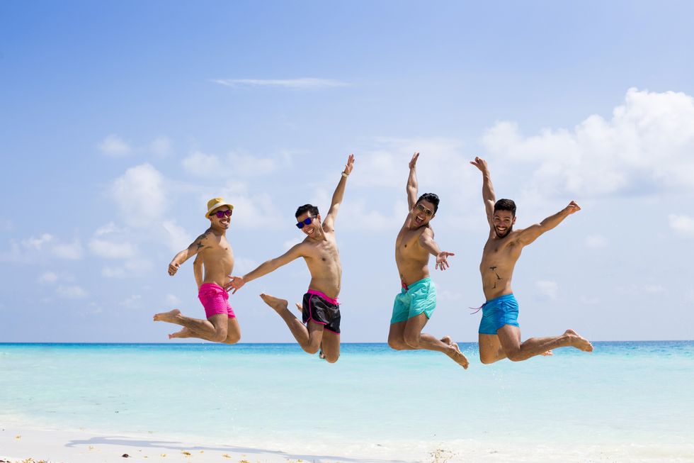four men jumping at the beach