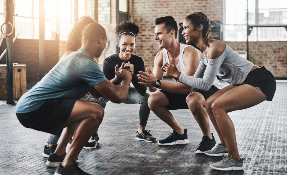 Friends, fitness and squat in group at gym for workout, core exercise or training together indoors. Diverse class, people and warm up for ab muscle, session or sport for health challenge in gymnasium