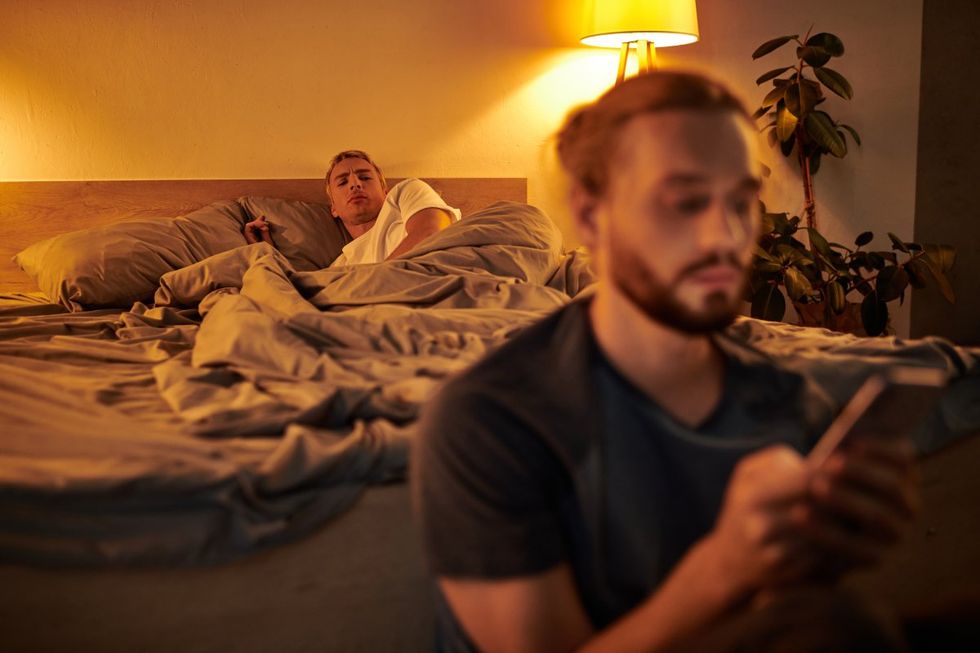 Gay couple, one watches suspiciously as the other looks at his phone