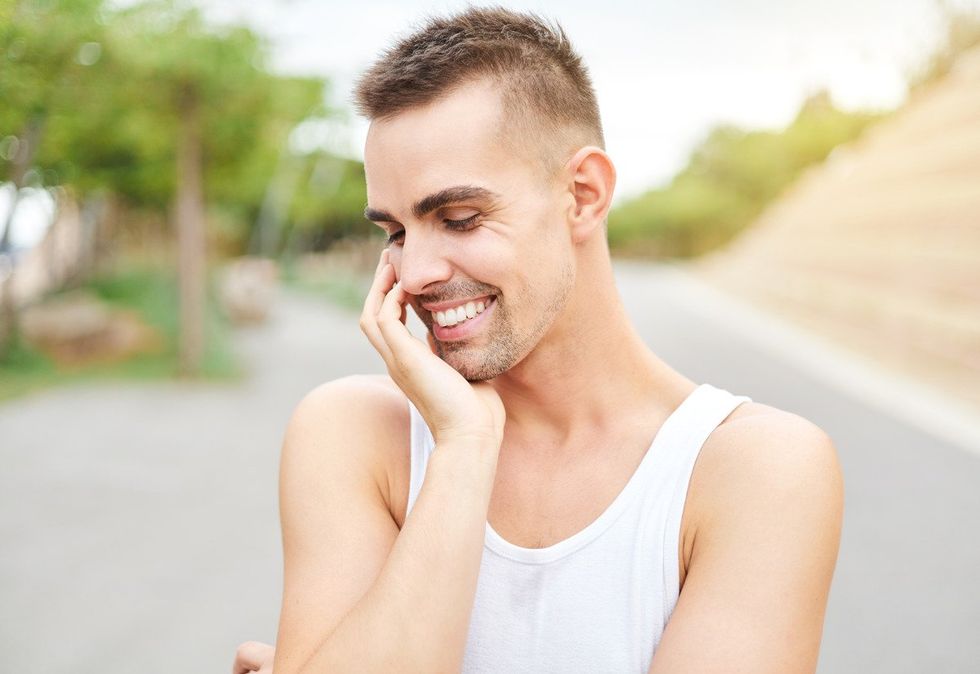 Gay man smiling and looking down with a complicity gesture.