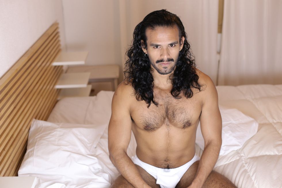 hairy man sitting on a bed in his underwear