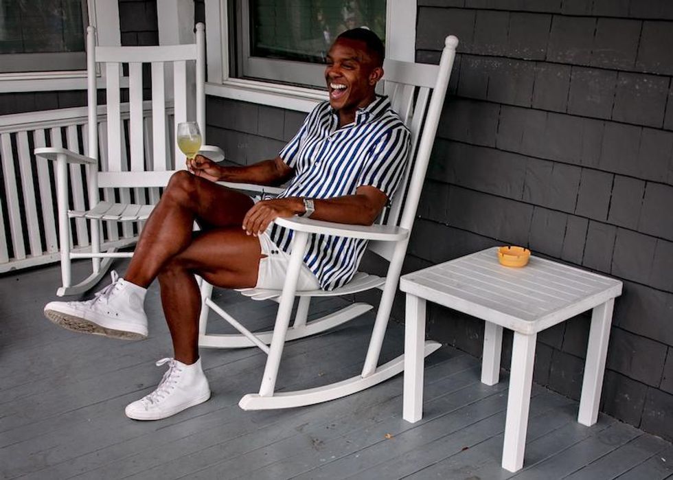 Happy man in summer attire sitting comfortably in a rocking chair on a porch 