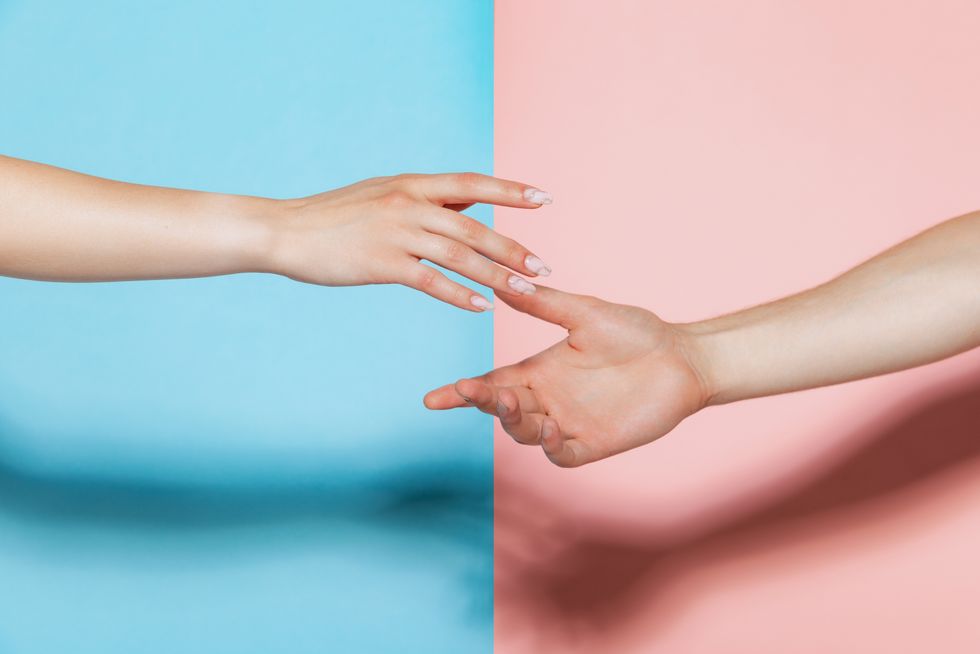 Image of male and female hands reaching each other isolated over pink blue studio background. Support. Concept of youth, emotions, facial expression, love, relationship. Poster, ad