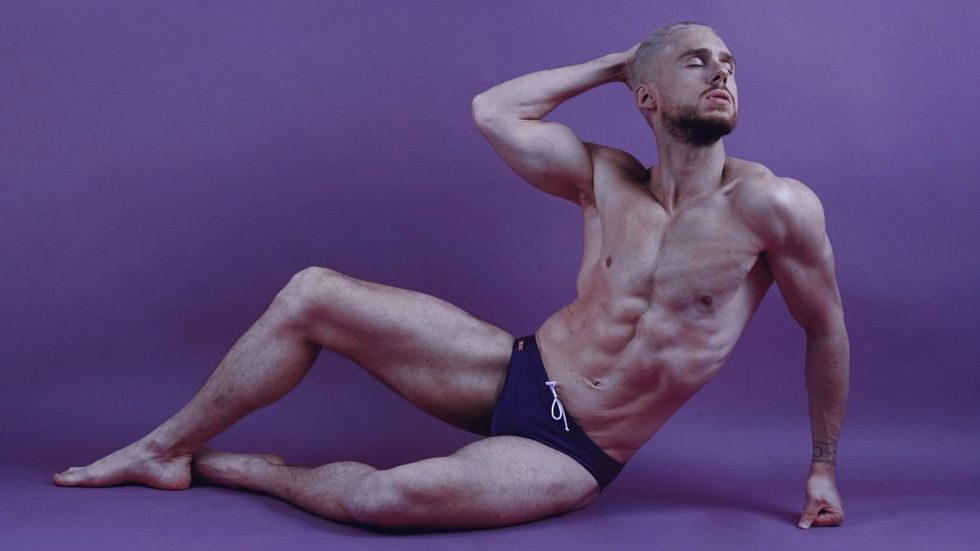 Jerome Prun poses in a speedo on a purple background