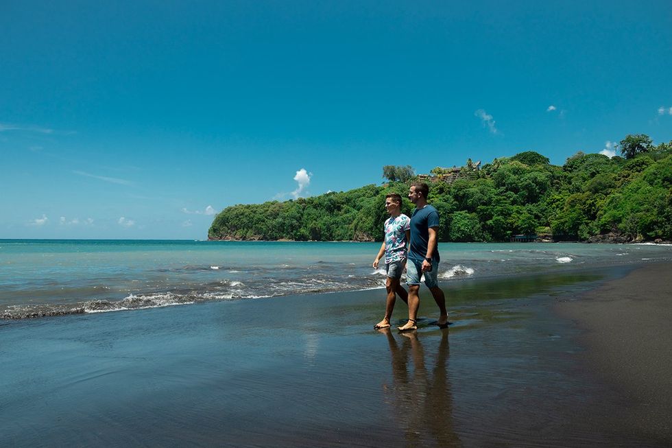 Lovers stroll along a Tahitian black sand beach