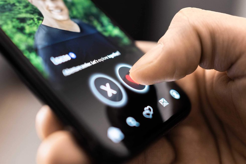 Male holding a cell phone with a dating app on it