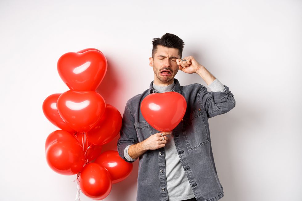 Man crying over a heart balloon