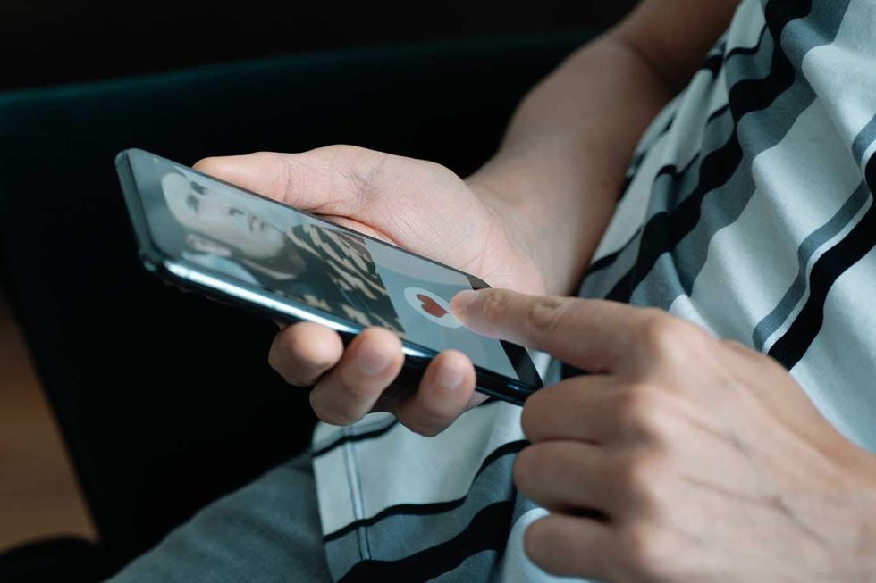 man holding a cell phone with a dating app on it