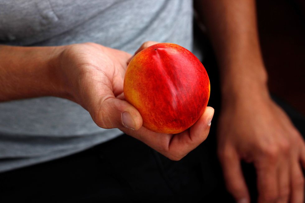 Man holding a peach.