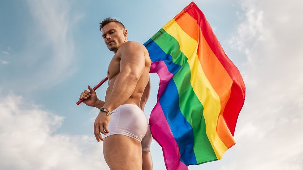 man in white shorts holding a rainbow flag