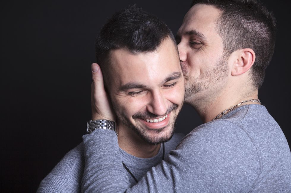Man kissing another man's cheek