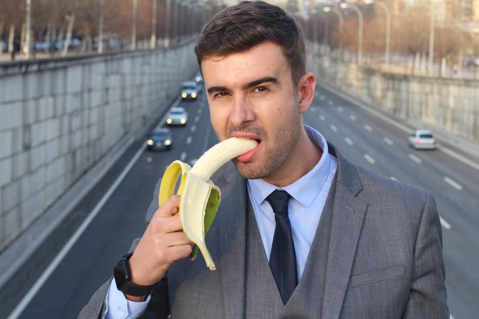 Man playfully biting a banana