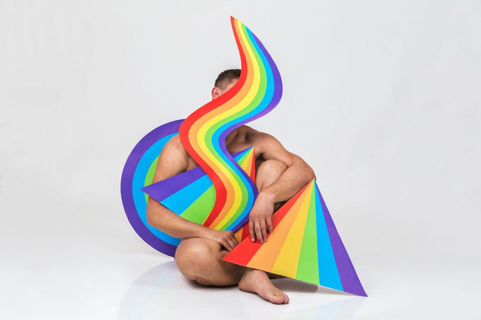 man posing behind rainbow paraphernalia