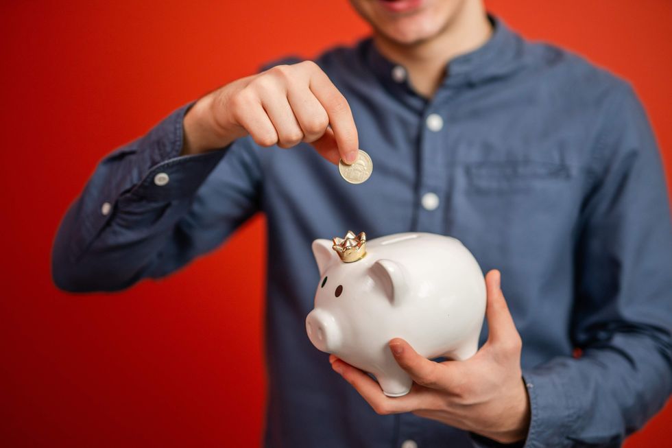 Man putting a coin into a piggy bank