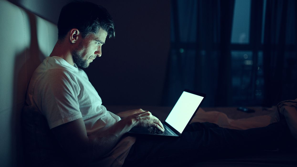 Man sitting in the floor with a laptop in his lap.