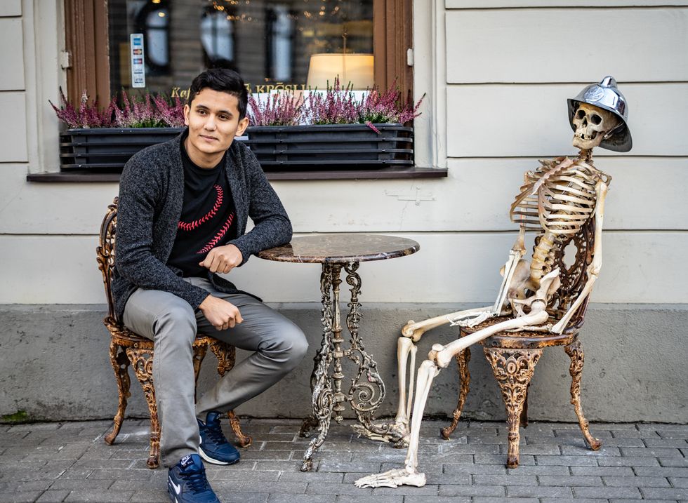 man sitting with a skeleton outside