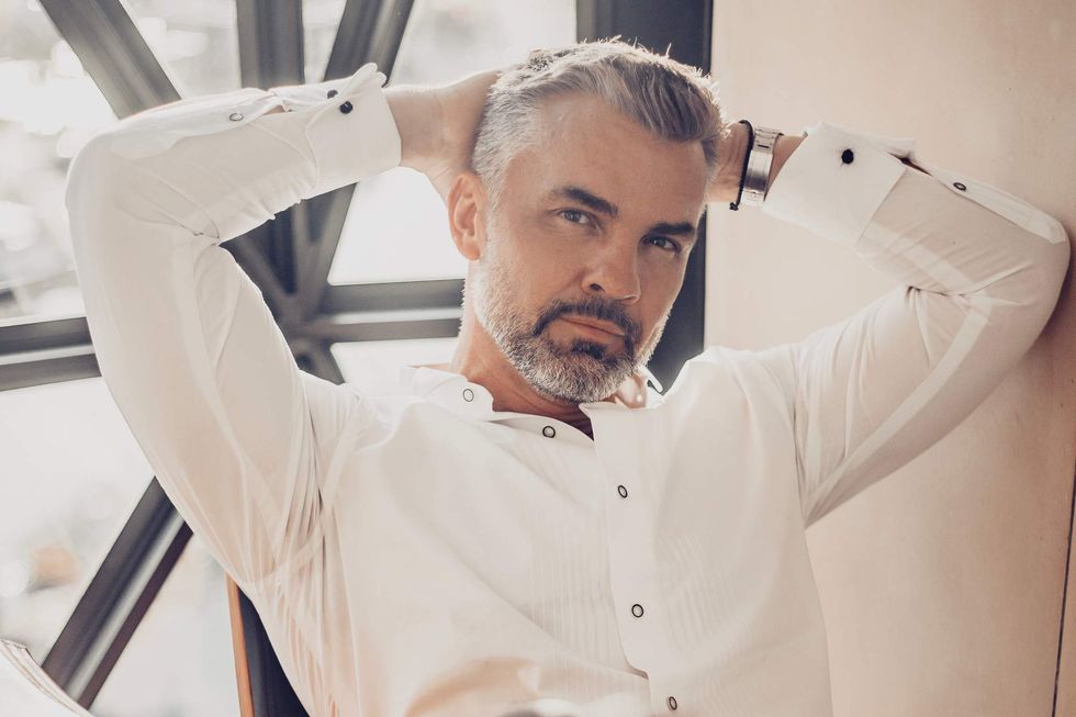Man with gray hair in a white shirt, leaning back, and looking at the camera.
