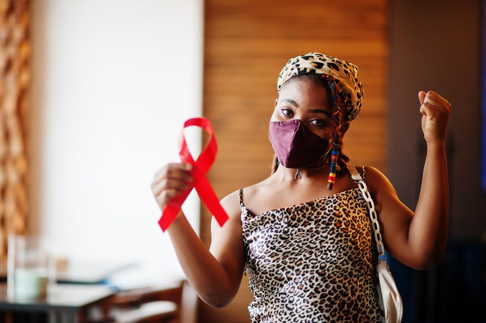 masked woman holding a red ribbon