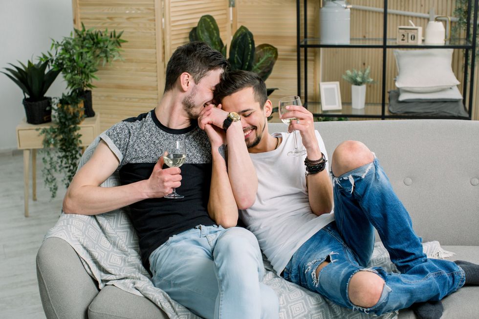 men cuddling on the couch with wine