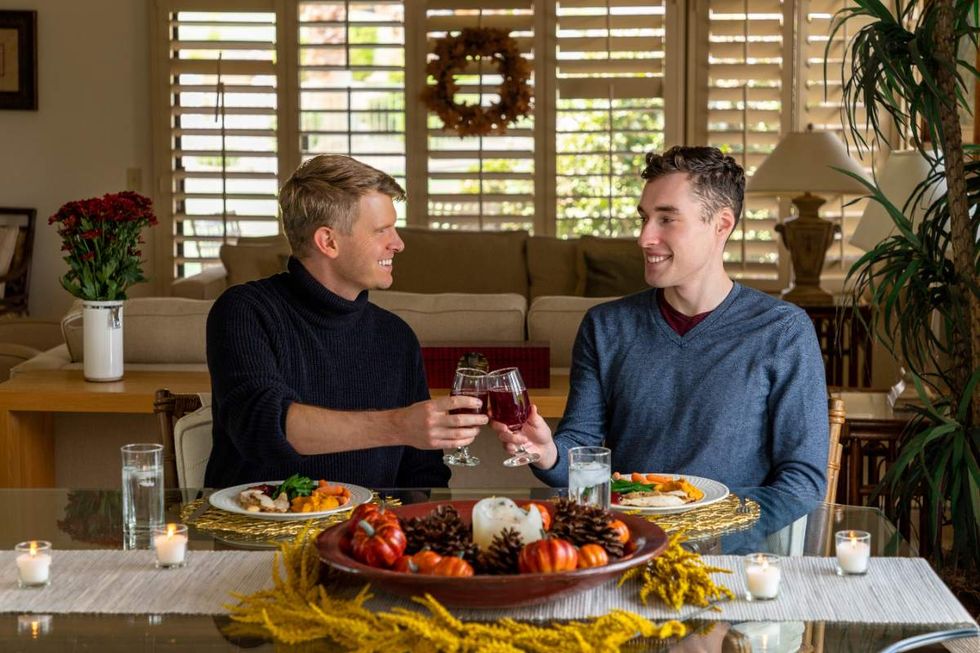 Men raise a glass of wine over thanksgiving dinner