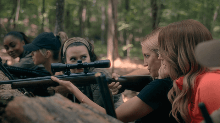 Monae, Taylor, Jill, and Margo Banks watch Sophie O'Neil prepare to fire her rifle in the woods, The Hunting Wives