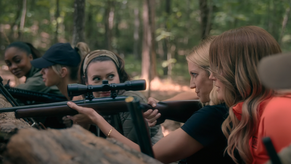 Monae, Taylor, Jill, and Margo Banks watch Sophie O'Neil prepare to fire her rifle in the woods, The Hunting Wives