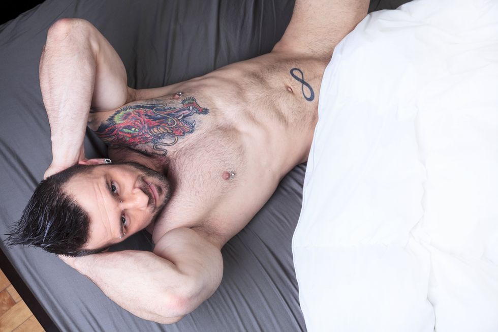 naked tatted man covering with a sheet