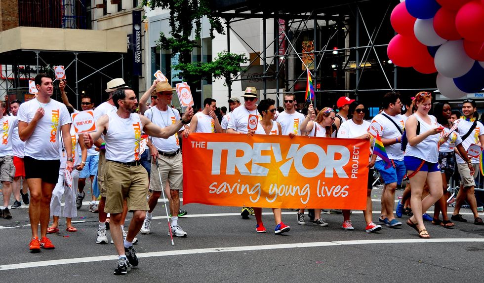 New York City - June 29, 2013: Members of The Trevor Project with their orange banner marching in the 2013 Gay Pride Parade on Fifth Avenue